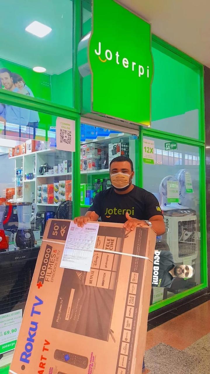 Colaborador Joterpi entregando uma Smart TV para cliente